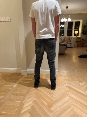 Feta svarta jeans - Snygga mörkgrå jeans med smal passform och klassisk femficksdesign. Jeansen har diskreta slitningar och kontrastsömmar, vilket ger en cool och modern look. Perfekta för dig som gillar en smal siluett och streetstyle.