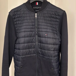 Svart pufferjacka Tommy Hilfiger M - Svart pufferjacka från Tommy Hilfiger i storlek M. Har använd ytterst få tillfällen så är så gott som ny!