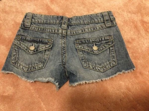 Blå jeansshorts från Gina Tricot - Säljer ett par blå jeansshorts från Gina Tricot med fransiga kanter och slitna detaljer. Shortsen har fem fickor, bälteshällor och knappstängning framtill. Perfekt för dig som gillar en chill och avslappnad stil på sommaren.