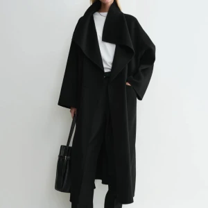 Svart lång kappa med bred krage - Säljer en svart, lång kappa med bred och snygg krage från TOTEME. Jackan har en loose passform och är perfekt för dig som gillar stilrena och minimalistiska plagg. Materialet  är wool- cashmere Ordinarie pris 9900.