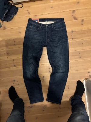 Acne Studios Blå Konst jeans blå - Säljer ett par mörkblå Acne Studios Blå Konst jeans. Mycket bra skick. Storleken passa W31 L30. Säljer för billigt pris för vill bara bli av med dem, jeansen har inga skavanker eller tecken på användning.