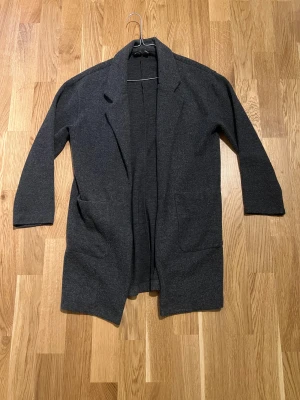 Lång Kappa/rock  - Lång grå kappa för kvinnor. Plagget är i ny skick utan några skador/slitningar, storlek S. Hör av er vid intresse/frågor. PRIS KAN DISKUTERAS!