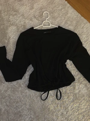 Svart långärmad topp - Säljer en svart långärmad topp från LCW Active i storlek XS. Passar även storlek S. Toppen har snörning i midjan för en justerbar passform, och är tajt vid armänderna. Passar till träning eller för vardaglig användning. Den har baggy passform. Gåva vid köp!🎁