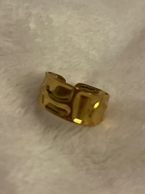 Guldfärgad ring ✨ chunky & vågig design - Trendig guldfärgad ring med bred, vågig och blank yta som ger ett modernt och statement-liknande uttryck ✨ Perfekt för dig som gillar chunky smycken men ändå vill ha en stilren look. ✨ Chunky & trendig ✨ Vågig/organisk design ✨ Statement-ring som lyfter hela outfiten I mycket fint skick 🤍 Skickas snabbt 📦 Skriv gärna om du har frågor eller vill ha fler bilder!