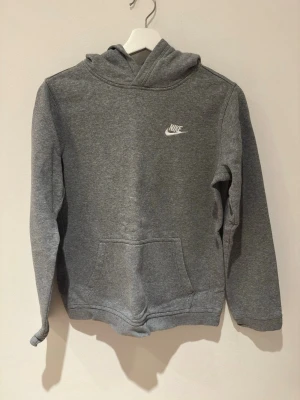 Hoodie - Grå hoodie från Nike. Finns tyvärr fläckar(med på bild 2&4) Storlek 158-170 motsvarar xs/s i vuxen storlek. Glömde ta bild på matchande byxorna som är i samma storlek, skriv gärna privat för att se byxorna