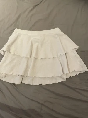 Volangkjol - Supersöt vit kjol med två lager volanger och elastisk midja. Materialet är mjukt och lätt, vilket gör dem riktigt sköna att bära under varma dagar.