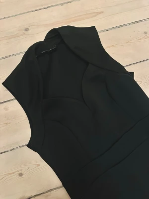 Svart figurnära klänning med slits - Den perfekta lilla svarta klänningen (little black dress). Fin urringning och liten slits på ena sidan. Använd en gång.