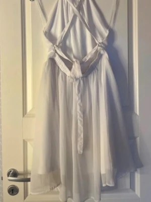 Vit kortklänning/ studentklänning  - Supersöt vit kortklänning från Make Way med halterneck och snygga korsade band i ryggen. Klänningen har omlottknytning bak och är tillverkad i ett lätt, flowy material som känns luftigt. Perfekt för sommarens alla tillfällen!