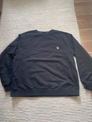 Svart sweatshirt med teddylogo från Copenhagen - Säljer en svart sweatshirt från Copenhagen med en färgglad teddylogo på bröstet. Tröjan har rund hals, långa ärmar och en relaxed passform. Perfekt för dig som gillar stilrena plagg med en twist. Materialet är mjuk bomull som känns skönt mot huden.