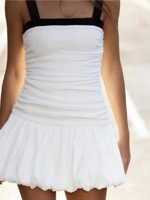 Trendig vit kortklänning från Zara - Supersöt vit kortklänning med svarta, breda axelband och fyrkantig ringning. Klänningen har en tight passform upptill och en voluminös, bubblig kjol. Perfekt för sommarens alla tillfällen eller student!🩷köpt här på Plick, helt ny och använd 1 gång! Köpte för 400 💕(kan disskutera pris vid snabb affär och intresserad köpare)💕 