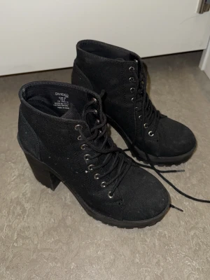 Svarta boots med klack från H&M - Säljer ett par svarta boots från H&M med grov klack och snörning framtill. Perfekta för dig som vill ha en edgy look och gillar chunky klackar.