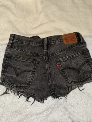 Svarta / mörkgråa Levi's shorts W25 - Säljer ett par svarta / mörkgråa jeansshorts från Levi's. Perfekta till sommaren och riktigt snygga, säljer då storleken inte passar mig längre.