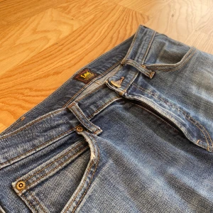 Blå Lee jeans med raka ben - Säljer ett par klassiska blå jeans från Lee med raka ben och normal passform. Jeansen har fem fickor, snygga slitningar och Lee-lapp bak i midjan. Tillverkade i slitstarkt denim med kontrastsömmar och dragkedjegylf. Kontakta ifall du har några frågor 