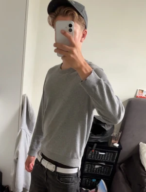 Grå långärmad tröja  - Snygg och enkel grå långärmad tröja med rund hals. Tröjan har en klassisk passform och som känns skön mot huden. Perfekt att matcha med jeans eller shorts för en clean och stilren look.