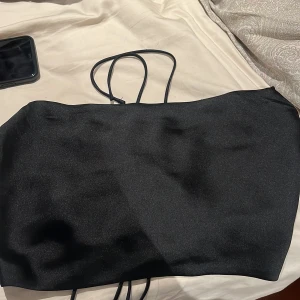 Svart crop top/festlig tröja från NA-KD - Snygg svart festlig/crop top från NA-KD i storlek 36. Den har en öppen rygg. Den är stor på mig å har aldrig kommit till användning 