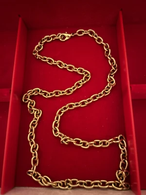 Kedjehalsband i guldton - Snyggt halsband med chunky kedja i guldton. Länkarna är ovala och har en blank finish som ger ett coolt och stilrent intryck. Perfekt för dig som gillar statement-smycken och vill addera lite extra edge till din look.