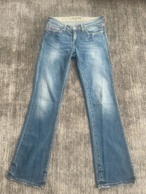 Blå bootcut jeans från Big Star - Snygga lågmidjade blåa jeans från bigstar med ljus slitningar och bootcut. W28 L33. Passar mig i längden som är 173. Innerbenslängd: 80cm Midjemått: 37 cm