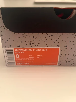 Nike Hypervenom x Jordan fotbollsskor - Nike Hypervenom x Jordan fotbollsskor i svart med röda och vita detaljer, nummer 23 broderat på sidan och Jumpman-logga på hälen. Skorna har högt skaft i stickad syntet, snörning och en platt sula med dobbar i beige och svart prickigt mönster. Snygg design för dig som gillar sport och streetstyle.