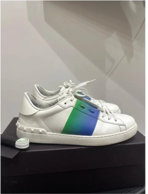 Valentino sneakers med blå-grön detalj - Snygga vita Valentino sneakers i skinn med en bred blå-grön färgskiftande panel på sidan. Skorna har klassisk snörning, rund tå och ikoniska nitar runt hälen. Perfekta för dig som vill sticka ut med en lyxig och modern touch.fetaste du har sett på marknaden.Exakt de guzzarna letar efter🥵