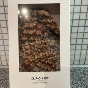 Rapunzel of Sweden spiral curls clip-on - Nytt och oanvänt Clip-on set med spiralformade lockar i caramel bronde highlights, 60 cm långt. Snyggt och naturligt resultat med volym och struktur, perfekt för dig som vill ha extra längd eller fyllighet. Fästs enkelt med clips och ger en cool look på bara några minuter. Nypris 4000kr ( köpt på kampanj för 2000kr) 