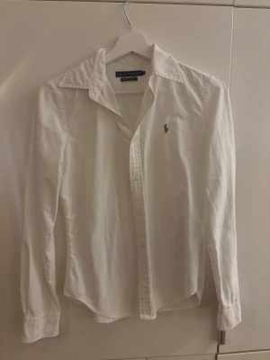 Vit skjorta Ralph Lauren  - Vit skjorta från Ralph Lauren med super slim fit-passform. Klassisk krage, långa ärmar och knappar framtill. Tröjan är knappt använd och därför tänkte jag att det är dags att sälja 💗
