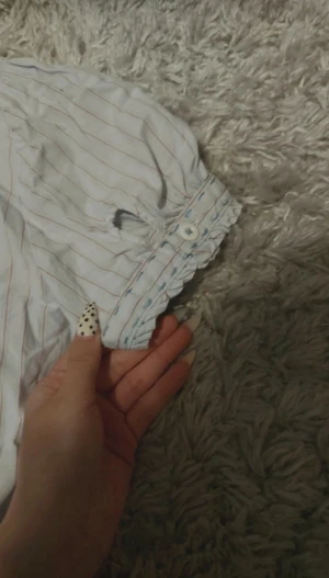 Randig kortärmad skjorta från Playboy - Snygg vit skjorta med röda ränder från Playboy, korta ärmar med puff och söt volangkant. Broderad Playboy-logga på bröstet och klassisk krage. Skjortan har knappar hela vägen och är gjord i mjuk bomull. Perfekt för dig som gillar statement-plagg med lite edge. Det står att den är L/XL men sitter mer som M.