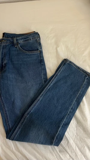Lee Daren Zip Fly Regular Straight jeans - Snygga klassiska blå jeans från Lee, modell Daren Zip Fly Regular Straight. Jeansen har rak passform, normal midja och är tillverkade av återvunnet denim med dragkedja i gylfen. Perfekt för dig som gillar tidlös stil och kvalitetsmaterial.