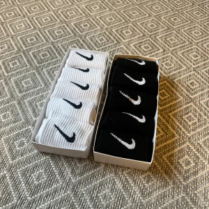 Nike strumpor svart & vit 10-pack - Säljer två paket Nike strumpor, 5 par svarta och 5 vita. Perfekt längd för sneakers och sport. Kommer i originalförpackning med 'Just Do It.'-tryck. Även köpta på en flygplats i England.