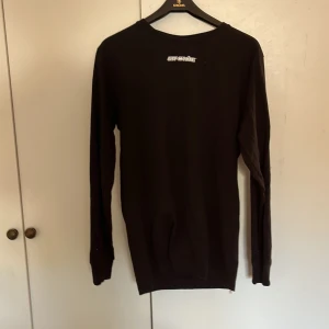 Svart långärmad Off-White tröja M - Svart långärmad tröja från Off-White med vit logga på bröstet och stort blått grafiskt tryck på ryggen. Den är i mycket bra skick och både påse med tags tillkommer. (jag är 191cm) sitter lite för litet på mig. Vid fråga är det bara och skriva. 