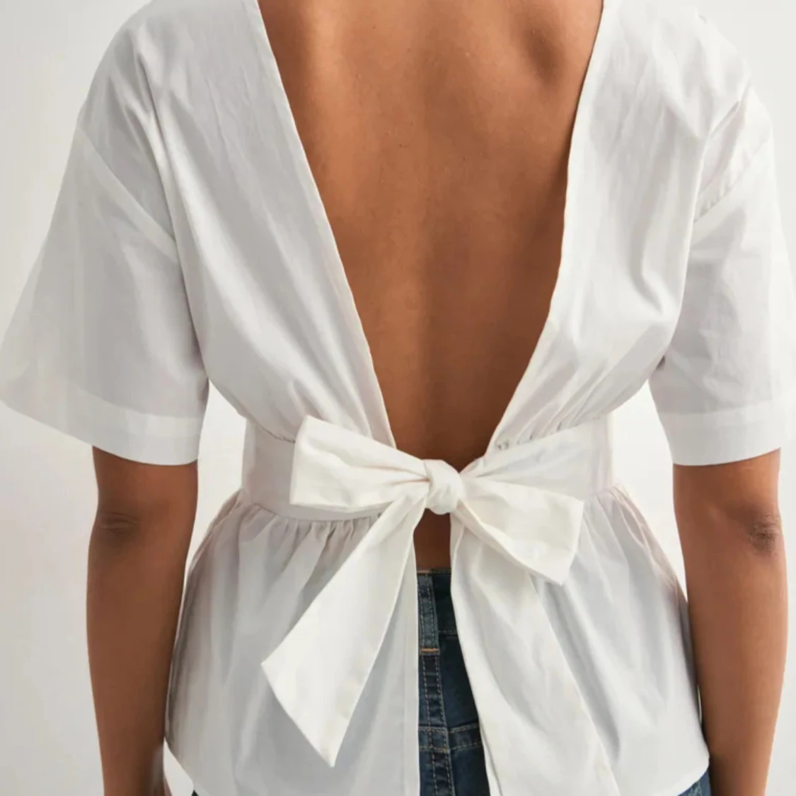 Vit blus med öppen rygg och rosett