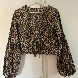 Leopardmönstrad blus med snörning - Säljer en leopardmönstrad blus från Nelly med ballongärmar och snygg snörning framtill. Blusen är ganska kort i modellen och har v-ringning!Superfin men kommer inte till användning därav annons. Nypris 299kr💗💗