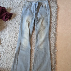 Ljusblå bootcut jeans - Säljer ett par ljusblå jeans med bootcut-modell. Jeansen har klassisk femficksdesign, normal midja och är tillverkade i mjukt denimtyg. Snyggt slitna detaljer framtill för en avslappnad look.