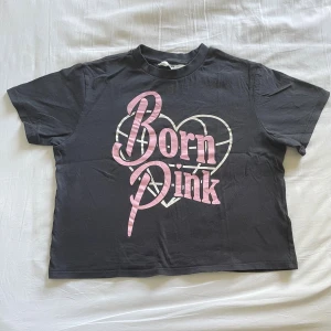 Blackpink t-shirt - Svart t-shirt med coolt rosa och vitt 'Born Pink'-tryck på bröstet och hjärtdetalj. Klassisk passform med korta ärmar och rund hals. Perfekt för dig som gillar statement-plagg. Gjord i mjuk bomull för skön känsla hela dagen.