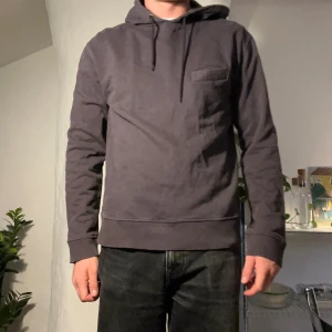 Hoodie l’homme rouge - Hoodie från l’homme rouge i deras mörka lila färg. Ficka på bröstet. Storlek XL men sitter lite mindre i passformen. Tyvärr liten mörk fläck på framsidan. Inte jättesynligt.