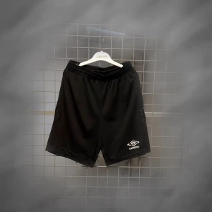 Svarta träningsshorts från Umbro - Svarta träningsshorts från Umbro med elastisk midja och klassisk logga på ena benet. Lätta och luftiga, perfekta för fotboll eller gymmet. Snygg sportig look och bekväm passform.