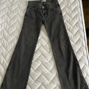 Grå/svarta bootcut jeans med raka ben - Snygga grå/svarta jeans med bootcut och raka ben. Klassisk femficksmodell med knapp och dragkedja framtill samt bakfickor med lock och knapp. Perfekta för dig som gillar en avslappnad men ändå stilren look.