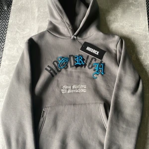 Grå hoodie från Hoodrich XS - Grå hoodie från Hoodrich med stor svart text på ryggen och broderade blå bokstäver på bröstet. Huva, känguruficka och trycket 'From Nothing To Something' framtill. Skön streetwear-stil och riktigt snygga detaljer.Pris går att diskuteras!