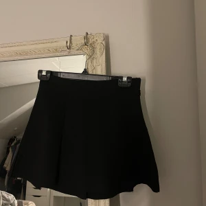 Svart minikjol  - svart kortkjol, med en lätt utsvängd form och är helt utan mönster eller detaljer. Storlek 146/152 men passar som xs/s