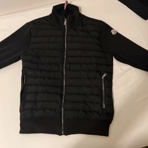 Svart moncler cardigan - Svart moncler cardigan i bra skick men tecken på användning’ Ena fickan har ingen zip annars e jackan perfekt. Priset går att diskutera så ge förslag endast vid seriöst affär