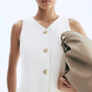 Vit väst med knappar och v-ringning - Stilren vit väst med v-ringad hals och fyra snygga knappar framtill. Storlek 36💕