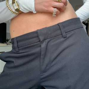 Svarta kostymbyxor från Nelly - Svarta kostymbyxor från Nelly i klassisk rak modell med låg midja. Byxorna har bälteshällor och stängs med dold dragkedja och hake. Snyggt skräddade och passar perfekt till en clean och stilren look.