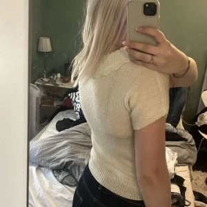 Söt stickad topp med spetskrage - Supersöt ljus stickad topp med korta ärmar och en bred, spetsinspirerad krage. Perfekt till jeans eller kjol för en gullig look. Mjuk och skön, passar perfekt till vår och sommar.