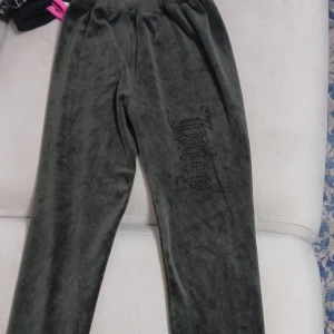 Mörkgröna Juicy Couture mjukisbyxor - Mörkgröna mjukisbyxor från Juicy Couture i sammetsliknande material. Byxorna har resår i midjan och dekoreras med glittriga svarta stenar som bildar Juicy-loggan på ena benet. Perfekta för en chill och trendig look. Kom dm för mera bild:)