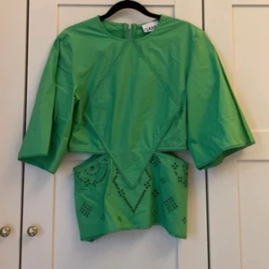 Grön blus med cutout från Ganni - Superfin grön topp från Ganni med vida trekvartsärmar och snygga broderade detaljer. 