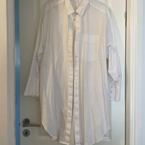 Vit oversized skjorta från H&M - Klassisk vit skjorta från H&M i oversized modell. Skjortan har lång ärm, bröstficka och knappar hela vägen framtill. Perfekt för en clean och stilren look. Tillverkad i mjuk bomull som känns skön mot huden.