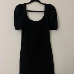 Svart kort puffärmad klänning - Stilren svart kortklänning med puffiga kortärmar och rundad urringning.