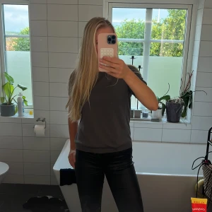 Mörkgrå basic stickad t-shirt - En stilren mörkgrå stickad t-shirt med klassisk passform och rund hals. Stickad t-shirten är kortärmad och har en enkel, clean look utan tryck eller mönster. Perfekt att matcha med jeans eller skinnbyxor för en avslappnad vibe.