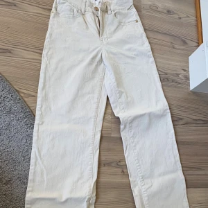 Vita raka jeans från Object - Säljer ett par vita jeans från Object med raka ben och hög midja. Byxorna har klassisk femficksdesign, bälteshällor och stängs med dragkedja och knapp. Materialet är kraftig bomull med en clean look, perfekt till sneakers eller boots.