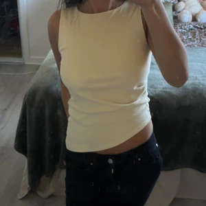 Ljusgul ärmlös linnetopp - Säljer en ljusgul, tight och ärmlös linnetopp med rund halsringning. Toppen är enkel och stilren. Mjuk och stretchig i materialet för en bekväm passform.