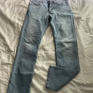 Levi's 502 ljusblå jeans W29 L32 - Ljusblå Levi's 502 jeans med klassisk femficksdesign och raka ben. Jeansen har normal passform och är tillverkade i slitstarkt bomullsjeans. Perfekta för dig som gillar en tidlös och clean look. Levi's-patch bak i midjan.